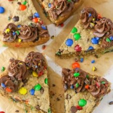 Overhead view of several slices of monster cookie cake on parchment paper.
