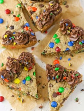 Overhead view of several slices of monster cookie cake on parchment paper.