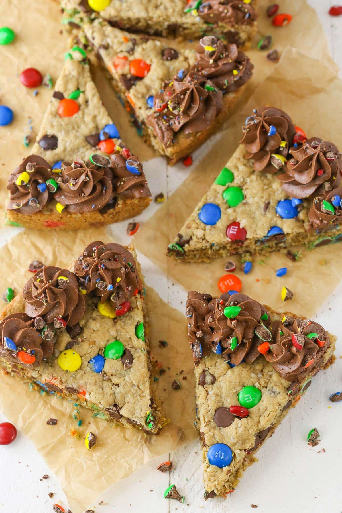 Overhead view of several slices of monster cookie cake on parchment paper.