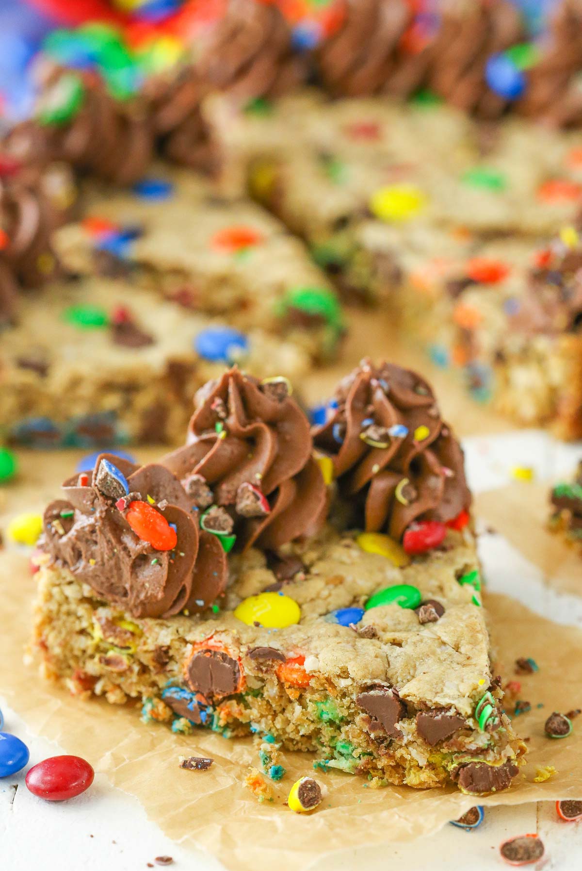 A slice of monster cookie cake on a piece of parchment.