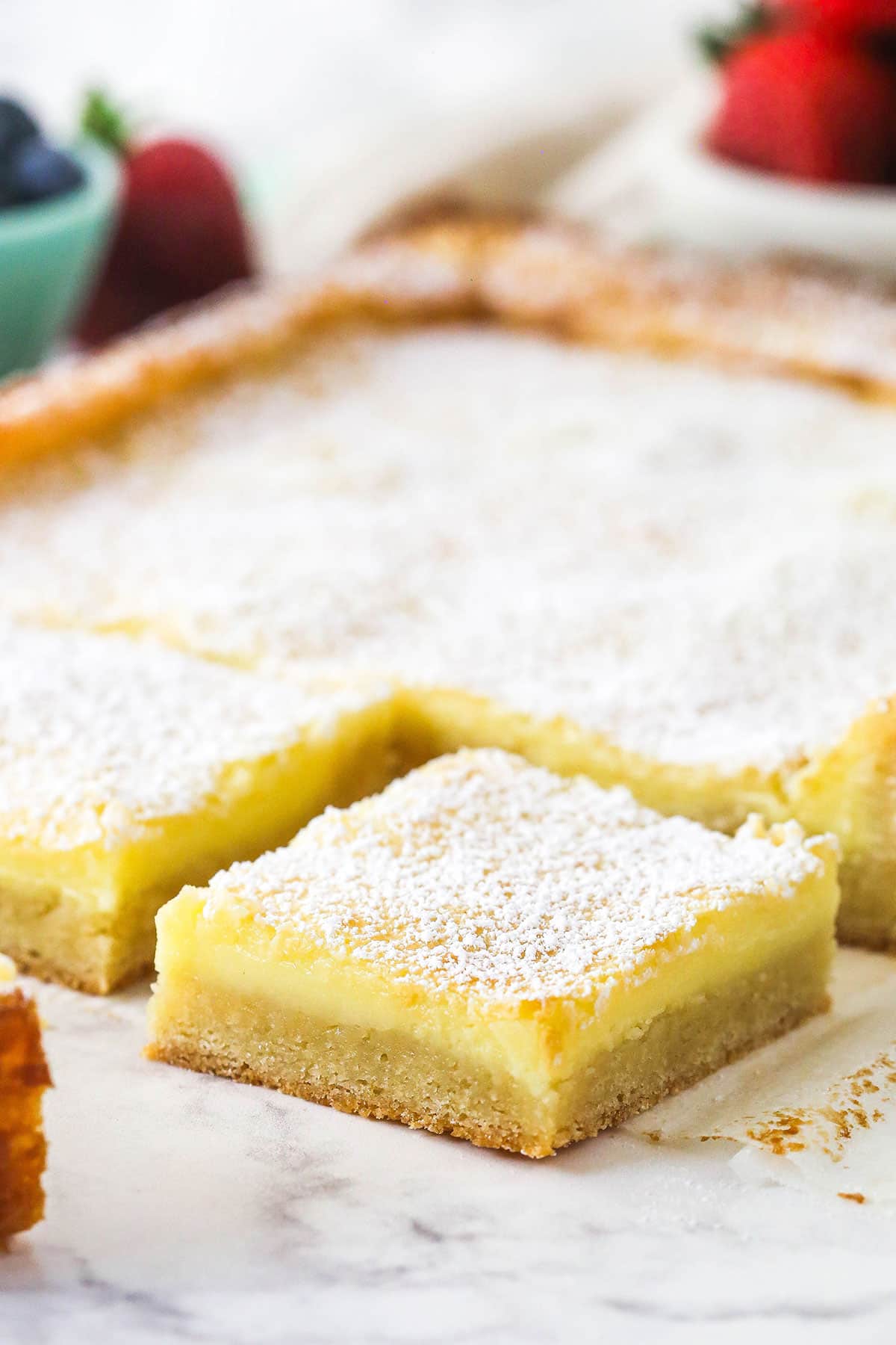 This from scratch Ooey Gooey Butter Cake is 100% irresistible with a rich, buttery, super moist cake layer and a silky cream cheese topping. A slice of ooey gooey butter cake cut away from the rest.