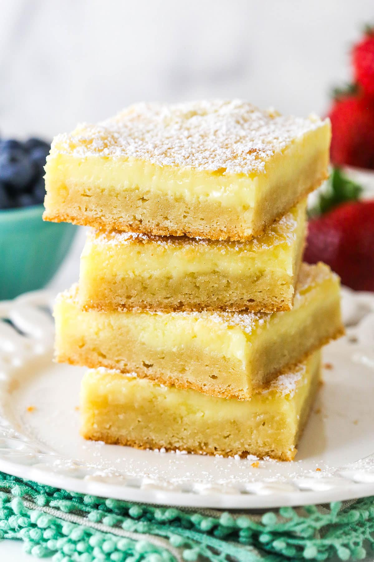 This from scratch Ooey Gooey Butter Cake is 100% irresistible with a rich, buttery, super moist cake layer and a silky cream cheese topping. Slices of ooey gooey butter cake stacked on a plate.