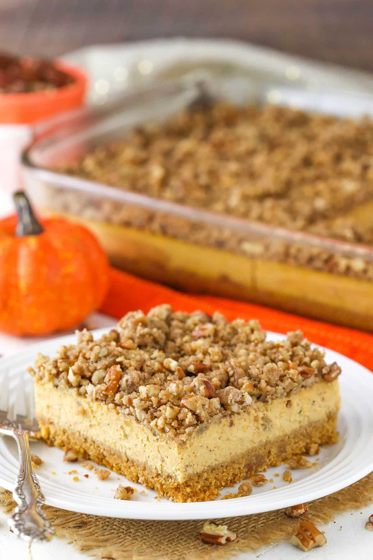 A slice of pecan streusel pumpkin cheesecake on a white plate.