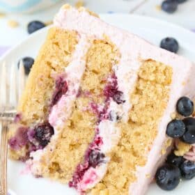 Close up of a slice of Blueberry Crumble Layer Cake on a white plate.