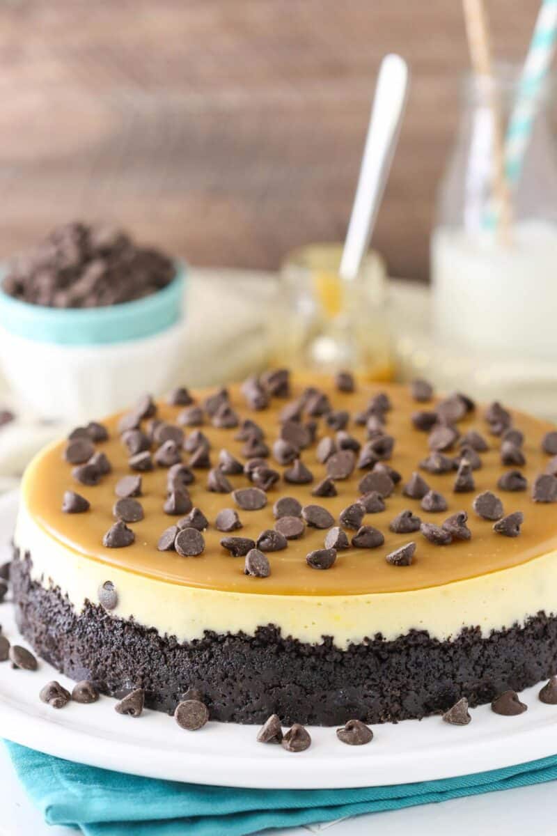 Side view of a caramel chocolate chip cheesecake on a white platter.