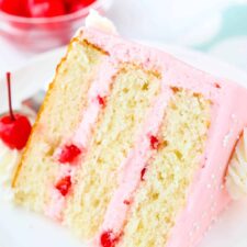 A slice of cherry almond layer cake laying on a white plate.