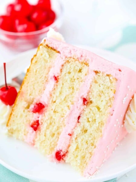 A slice of cherry almond layer cake laying on a white plate.