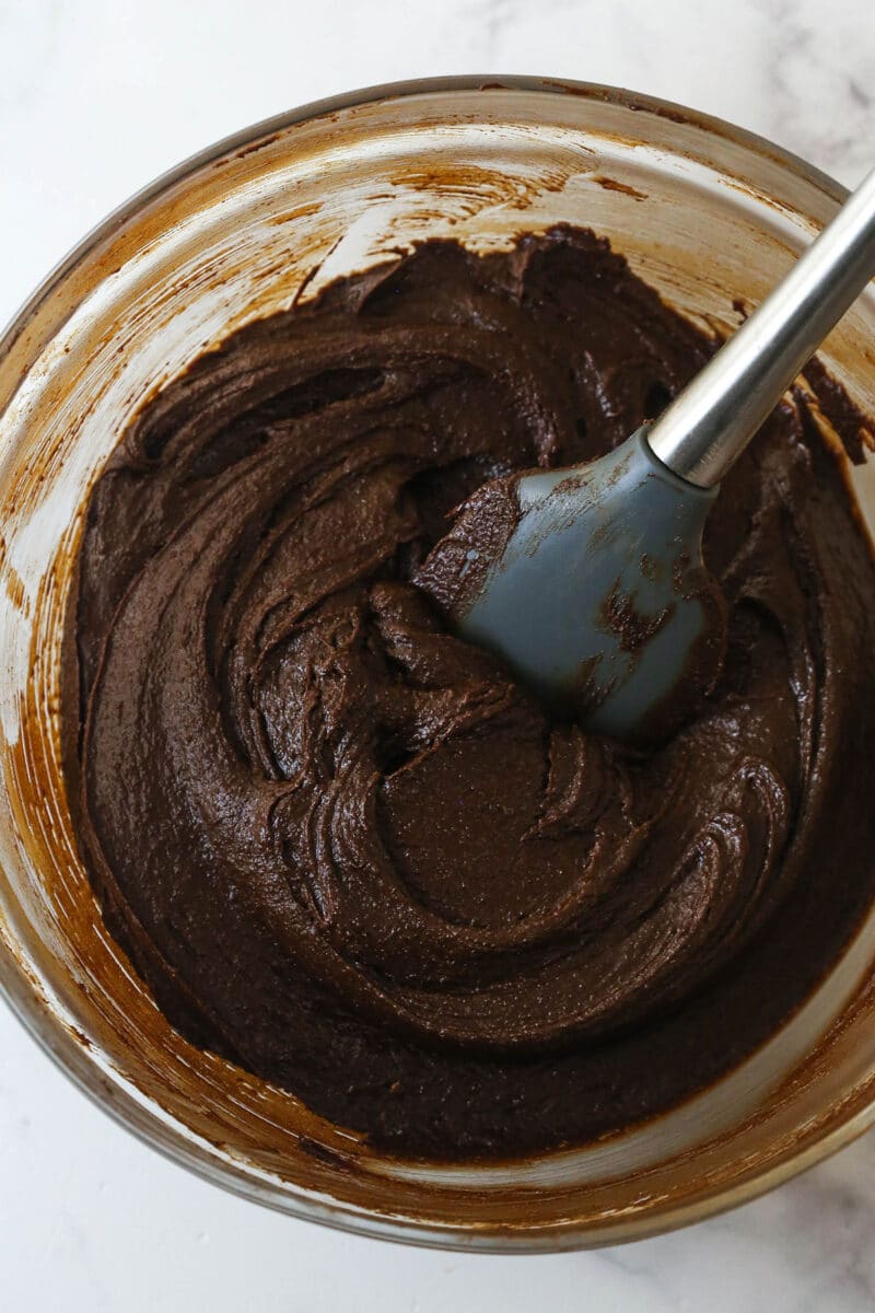 These nostalgia-filled, from-scratch Cosmic Brownies feature a fudgy brownie base topped with silky ganache and colorful sprinkles. Folding cocoa, flour, and salt into cosmic brownie batter.