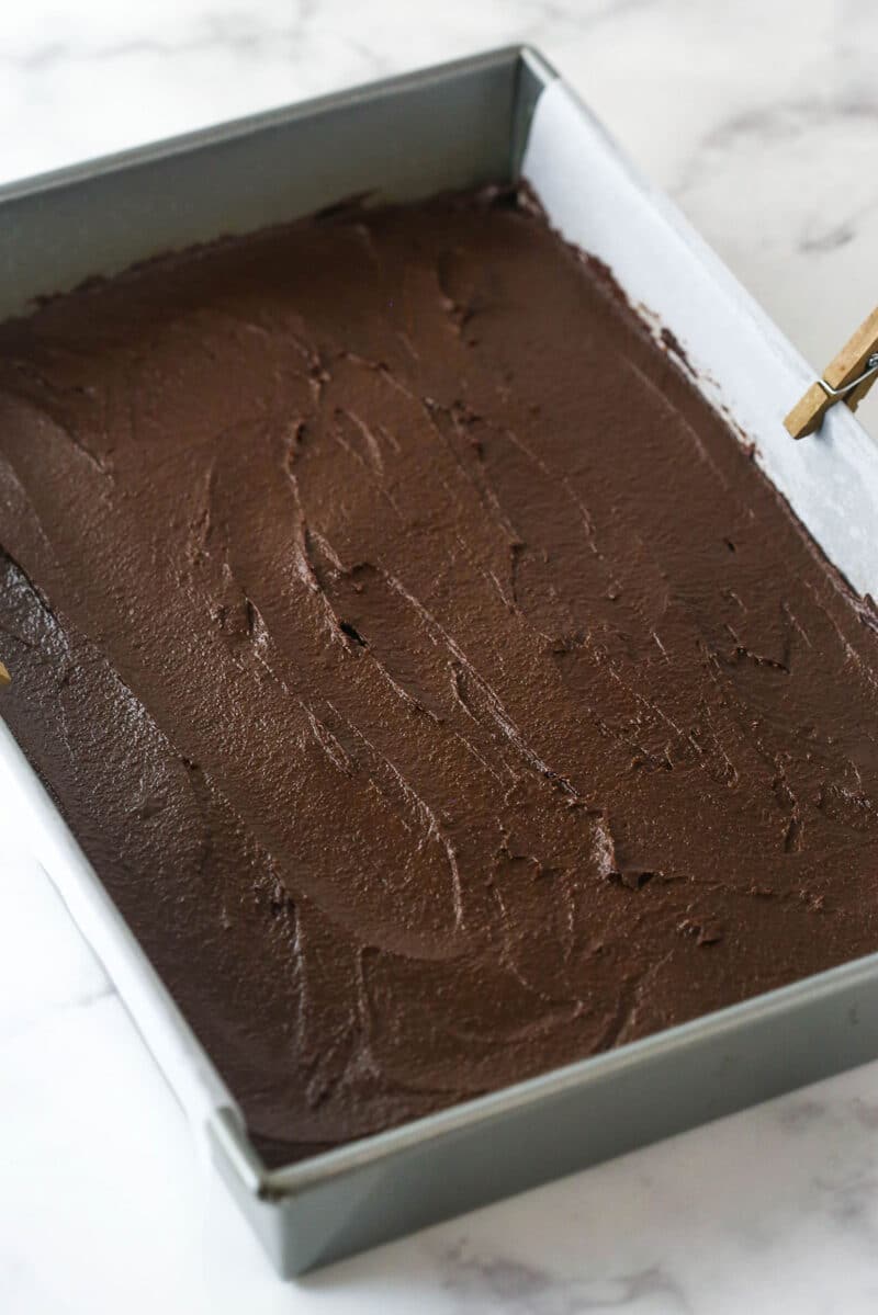 These nostalgia-filled, from-scratch Cosmic Brownies feature a fudgy brownie base topped with silky ganache and colorful sprinkles. Spreading cosmic brownie batter into a baking pan.