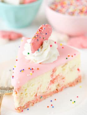 A slice of frosted animal cookie cheesecake on a white plate.