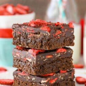 Three fudgy strawberry brownies stacked one on top of the other.