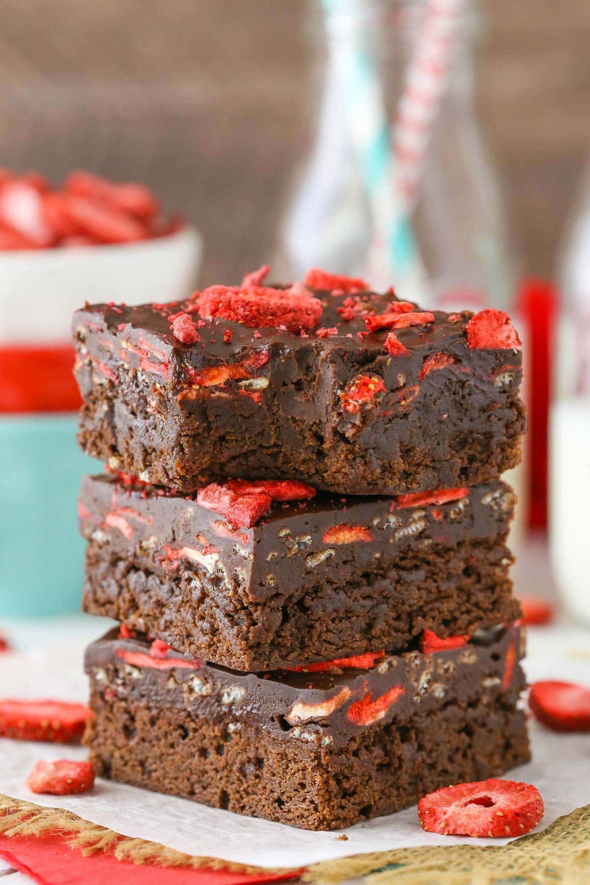Three stacked fudgy strawberry brownies with a bite removed from the top brownie.