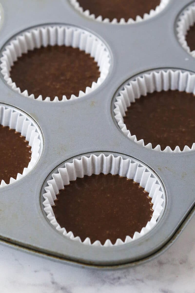 Chocolate cupcake batter in cupcake liners in a cupcake pan.