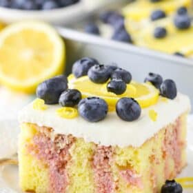 A slice of lemon blueberry poke cake on a white plate.