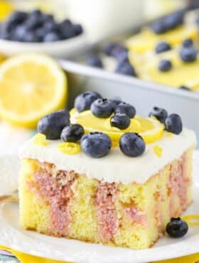 A slice of lemon blueberry poke cake on a white plate.