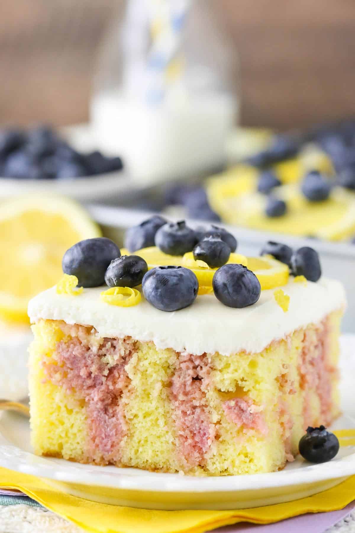 A slice of lemon blueberry poke cake on a white plate.
