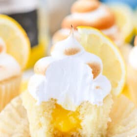 Close up of a lemon meringue cupcake with a bite removed to show filling.