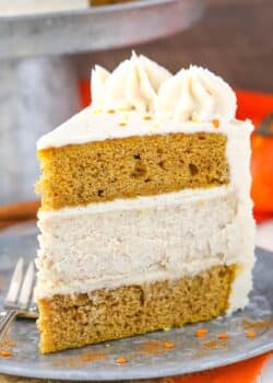 A slice of pumpkin cheesecake layer cake on a silver plate.