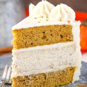 A slice of pumpkin cheesecake layer cake on a silver plate.