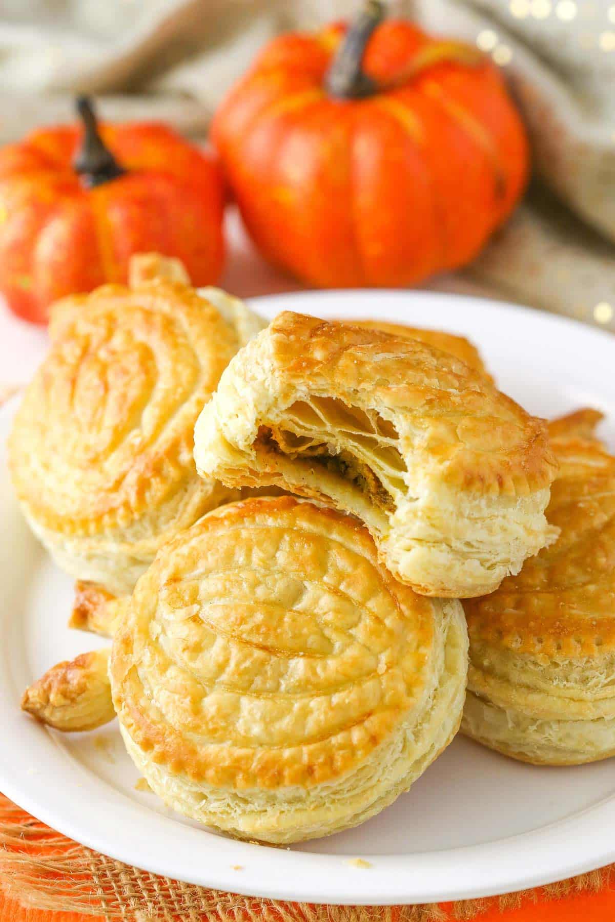 A plate of pumpkin spice pumpkin pastries with a bite taken out of top pastry.