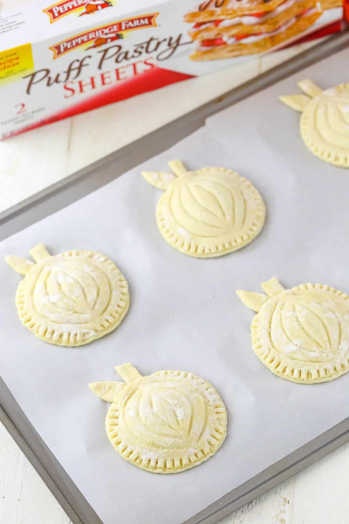 Assembled pumpkin spice pumpkin pastries on a baking sheet.