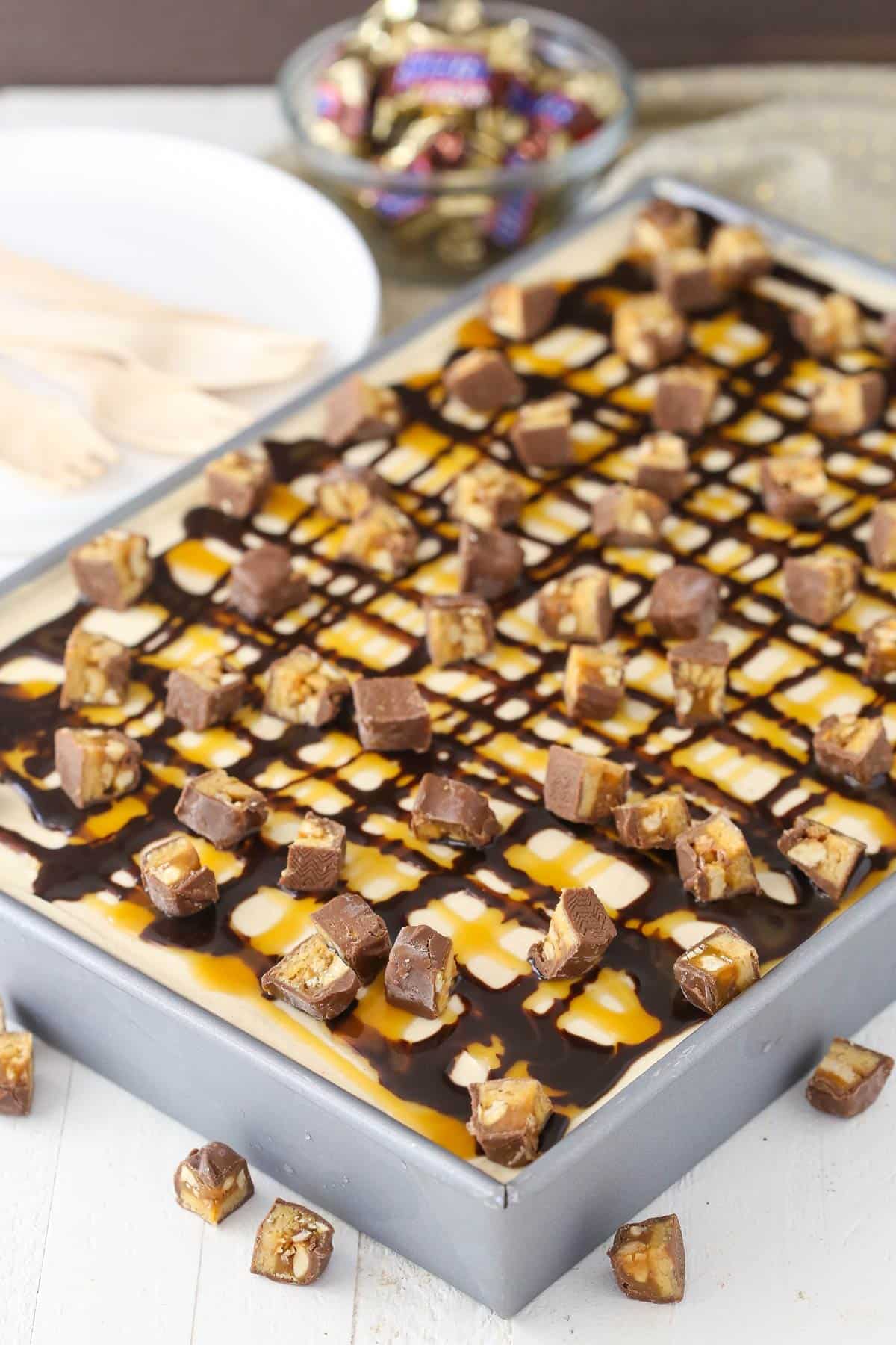 A snickers poke cake in a silver pan.