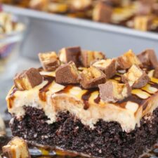 Close up of a slice of snickers poke cake on a silver plate.
