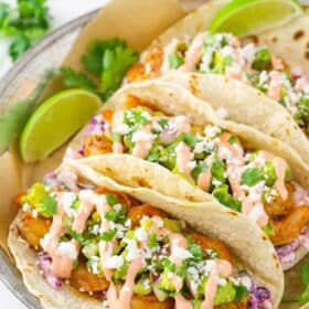 Three spicy sriracha shrimp tacos on a silver plate.