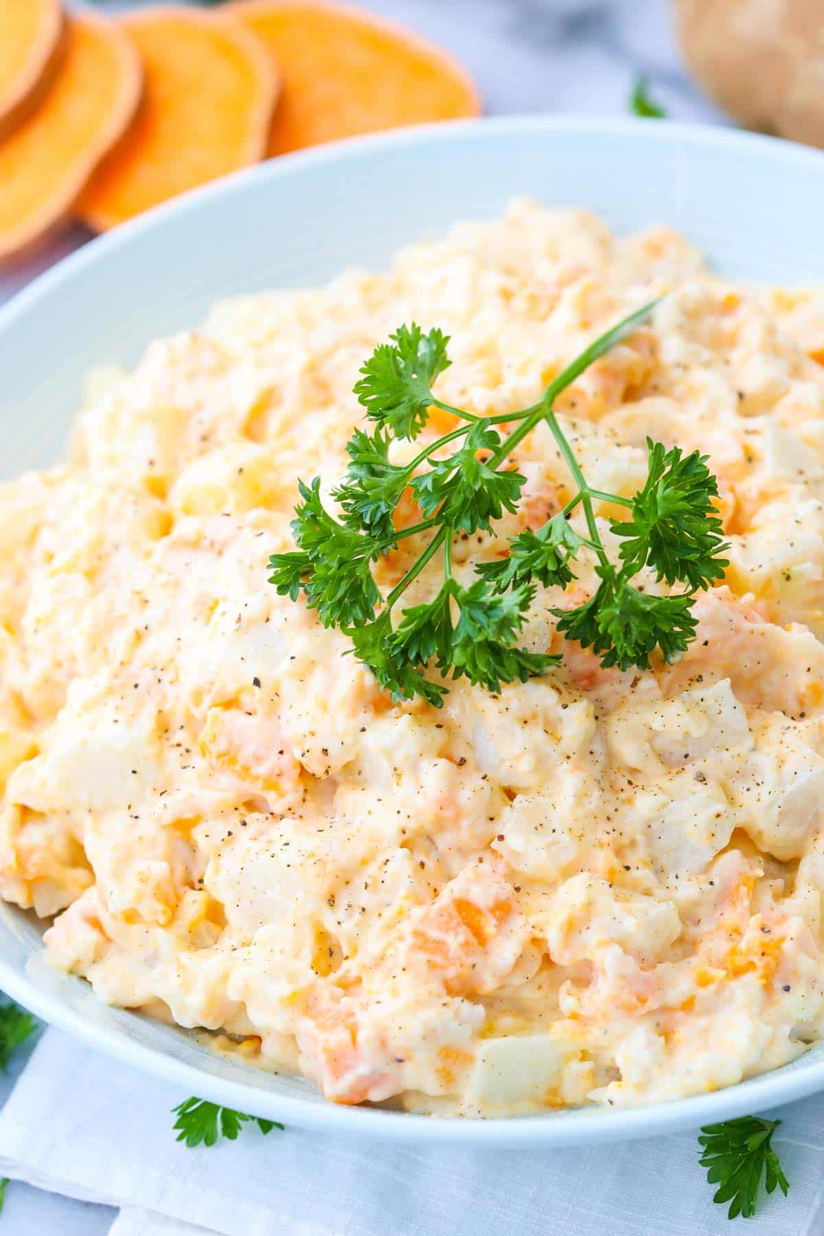 A bowl of three potato salad with parsley on top.