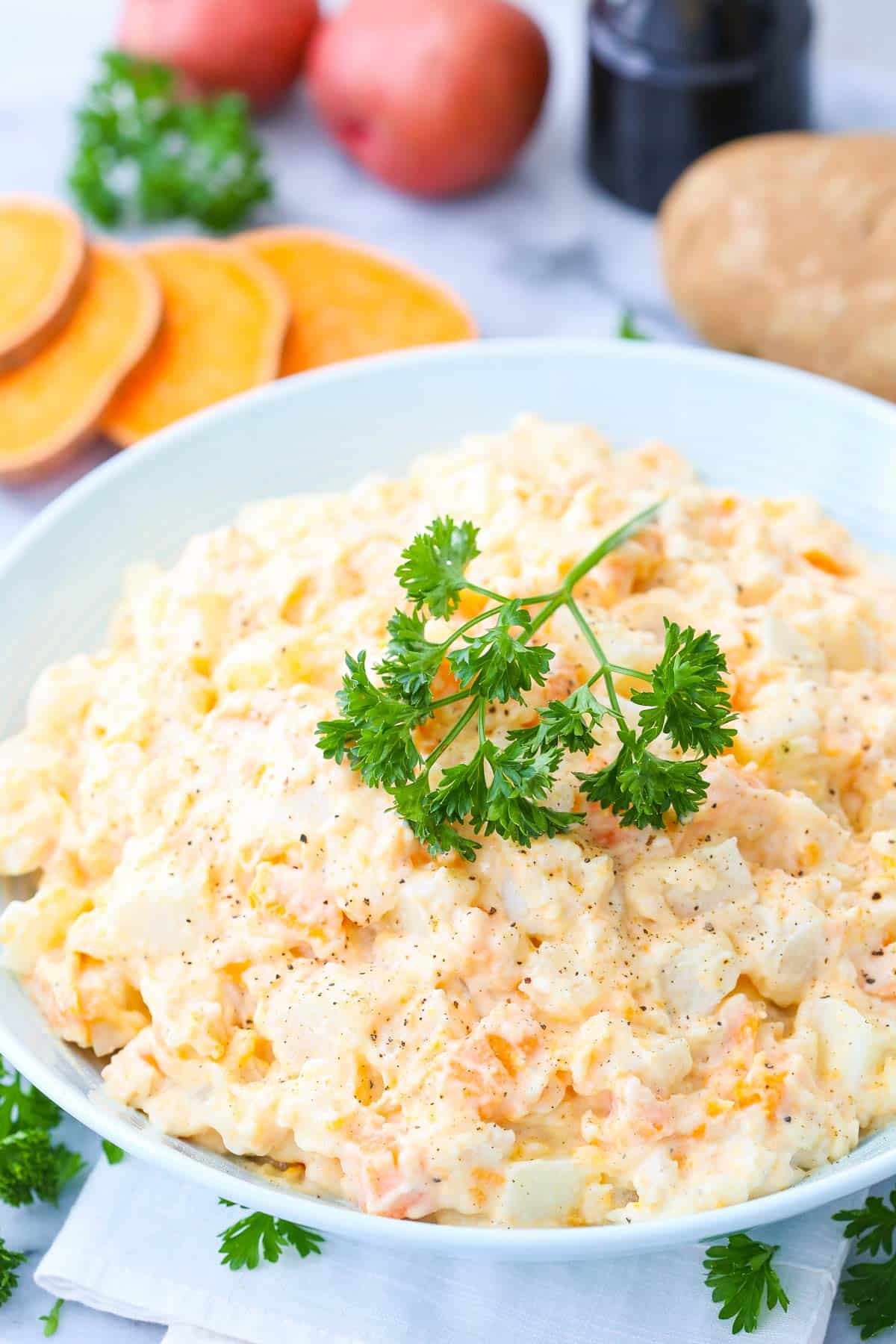 A bowl of three potato salad with parsley on top.