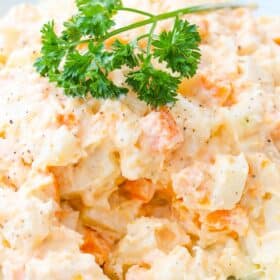 Close up of a bowl of three potato salad with parsley on top.