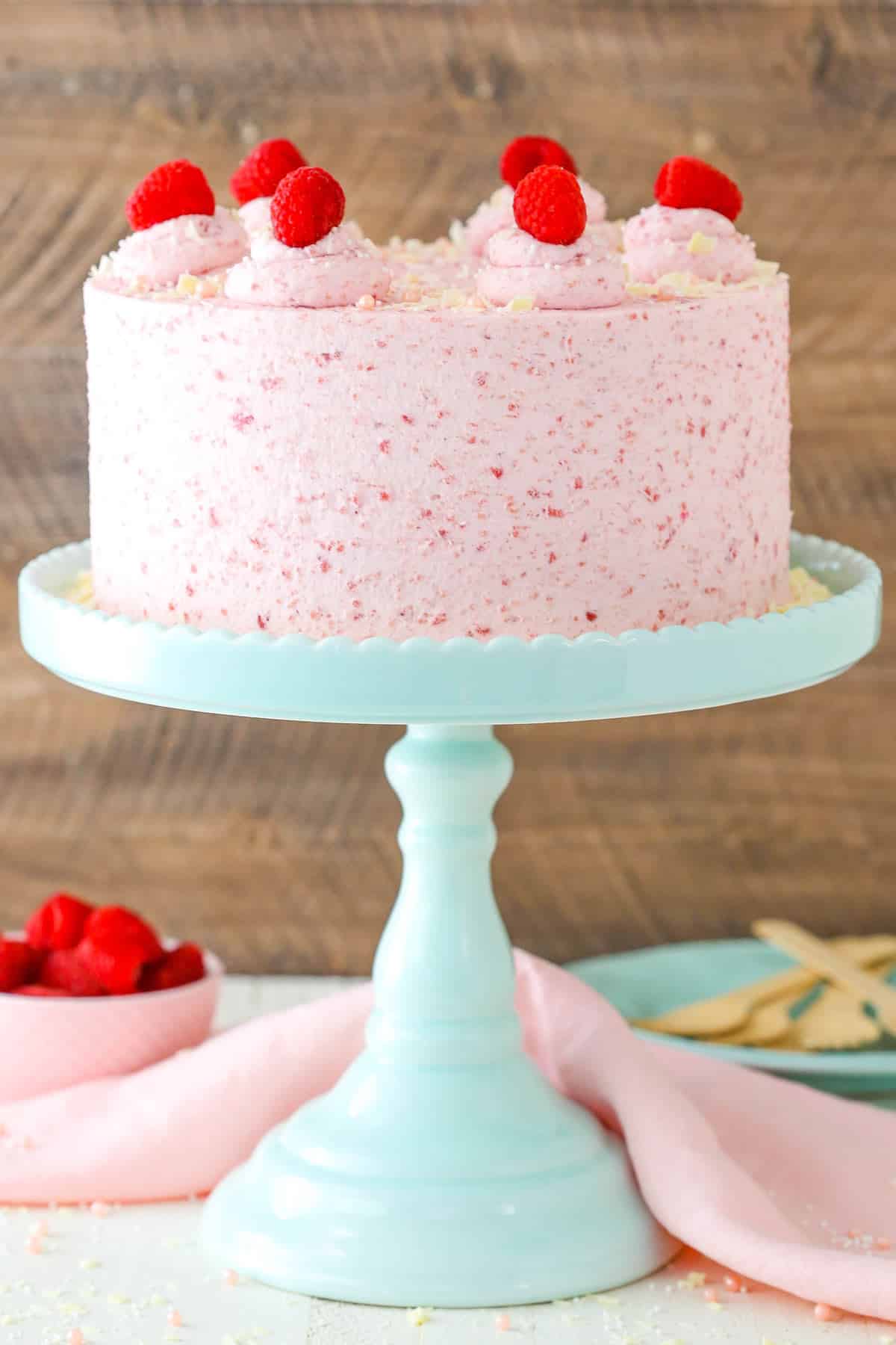 A white chocolate raspberry mousse cake on a teal cake stand.