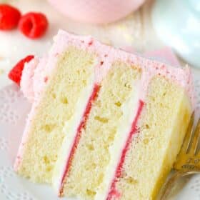 A slice of white chocolate raspberry mousse cake on a white plate.
