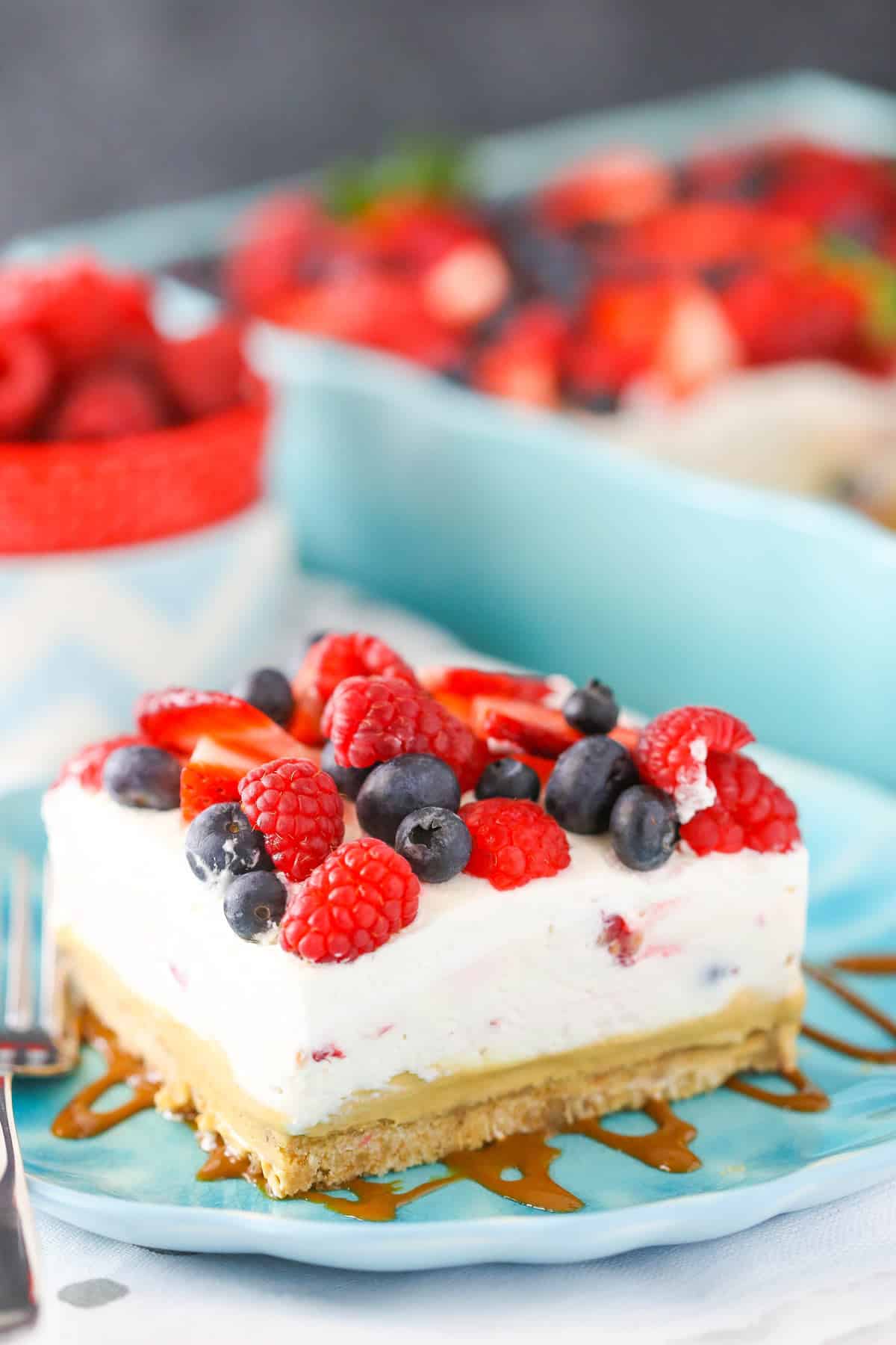 A slice of berries and cream layer dessert on a teal plate.