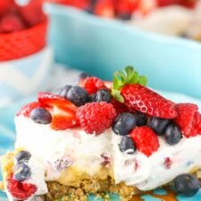 A slice of berries and cream layer dessert on a teal plate.