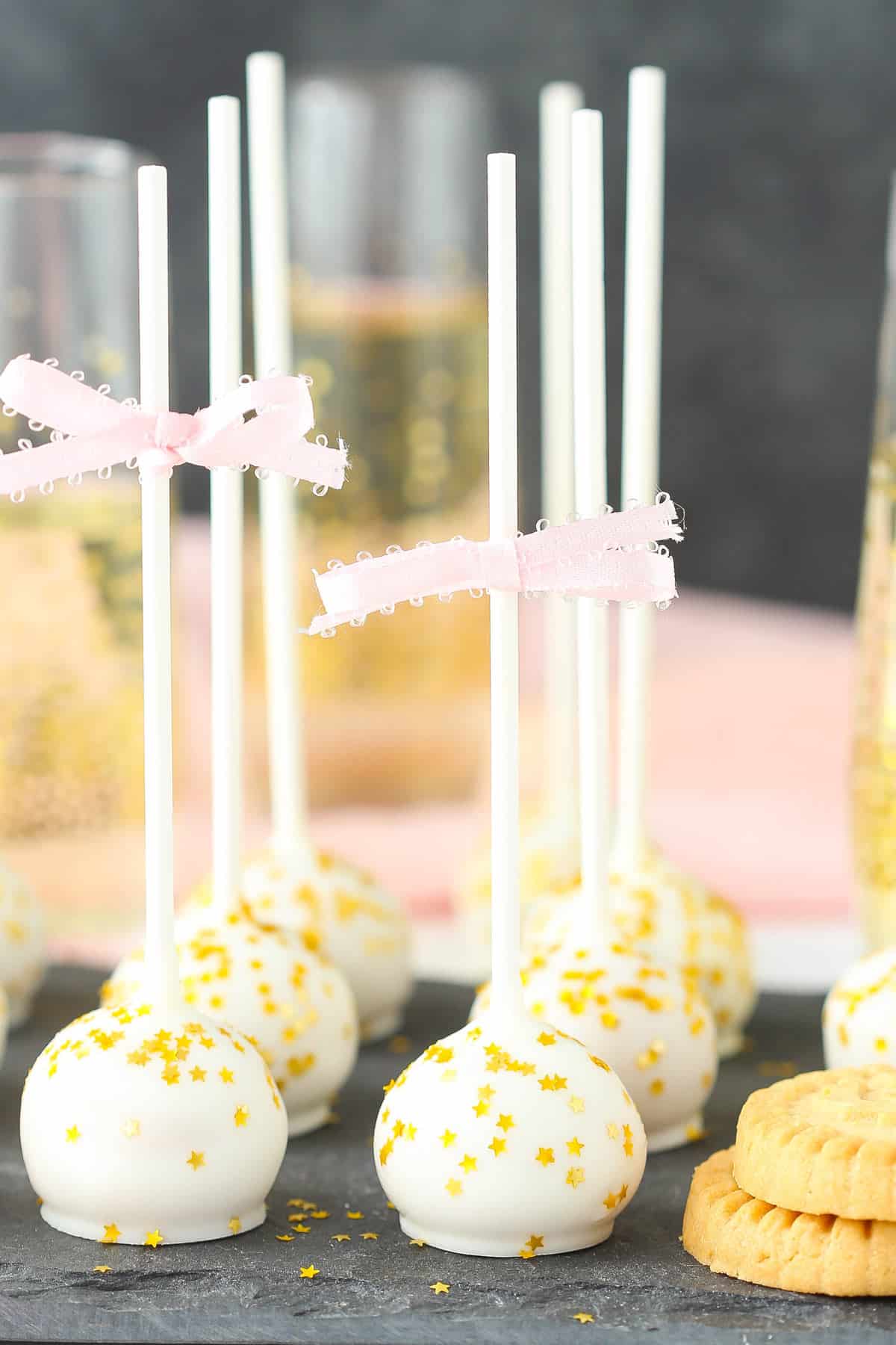 Several no bake champagne cookie pops on a granite slab.