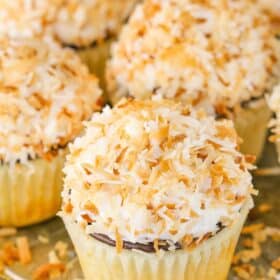 Several coconut macaroon cupcakes on a silver tray.