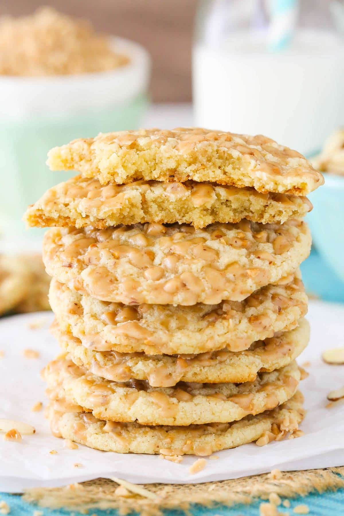 Close up of a stack of six gluten free toffee almond cookies with the top cookie broken in half.
