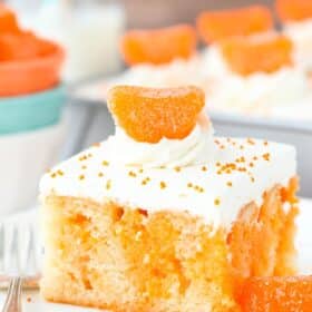 Close up of a slice of orange creamsicle poke cake on a white plate.