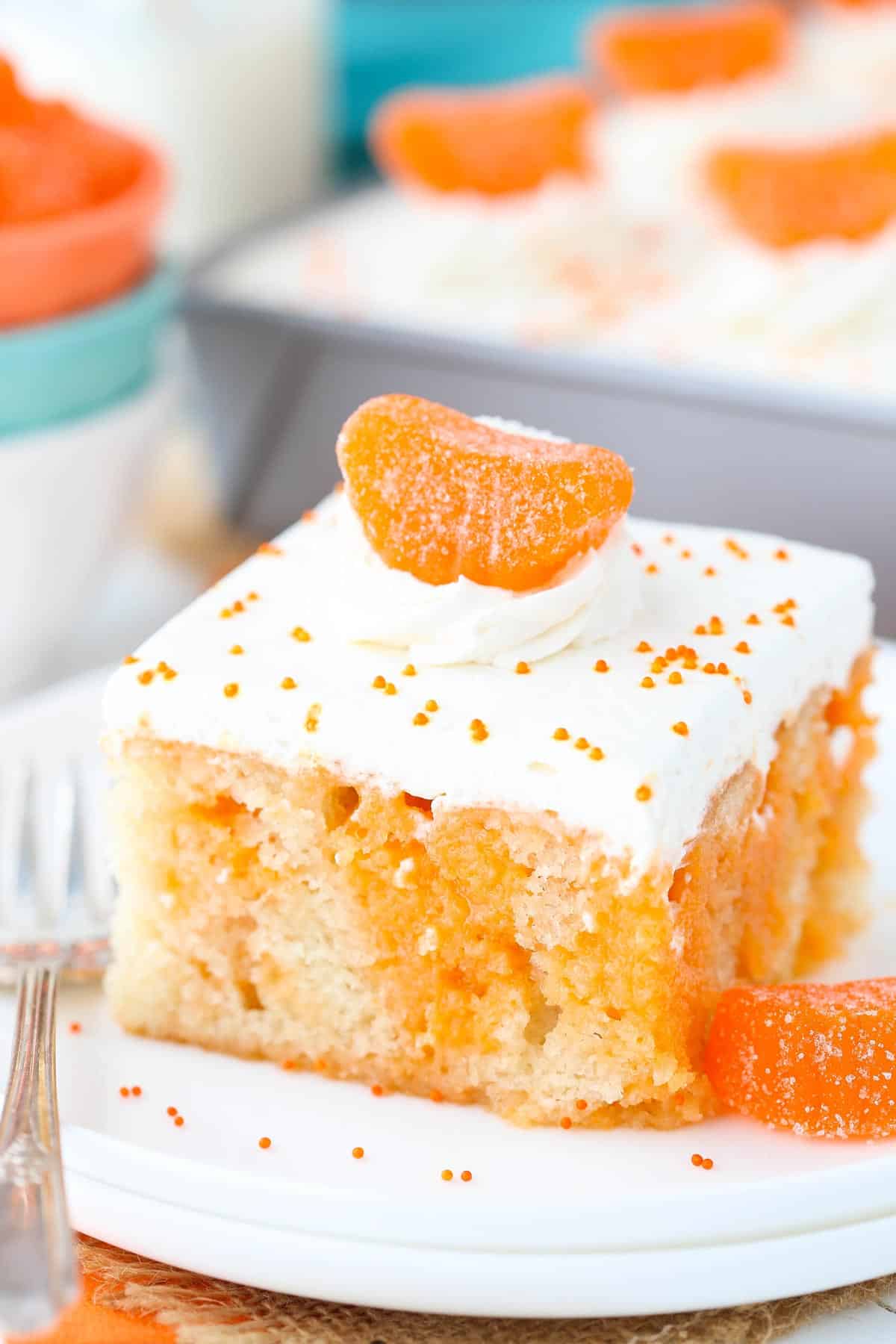 A slice of orange creamsicle poke cake on a small white plate.