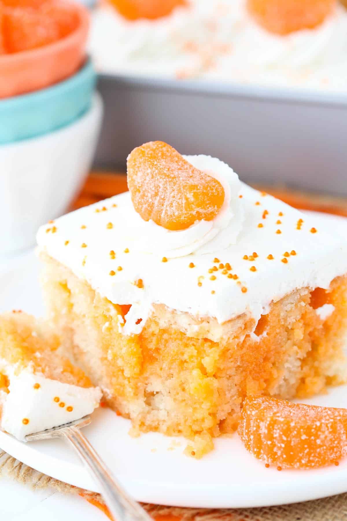 Close up of a slice of orange creamsicle poke cake with a bite removed on a fork.