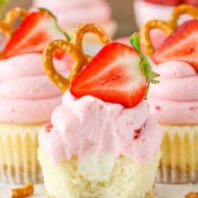Close up of a strawberry pretzel salad cupcake with a bit removed to show layers and center.