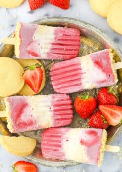 Close up of four strawberry shortcake popsicles on a silver tray.