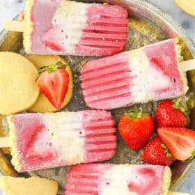 Close up of four strawberry shortcake popsicles on a silver tray.