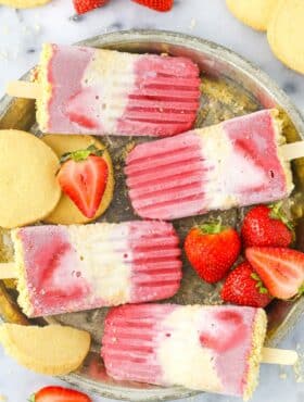 Close up of four strawberry shortcake popsicles on a silver tray.