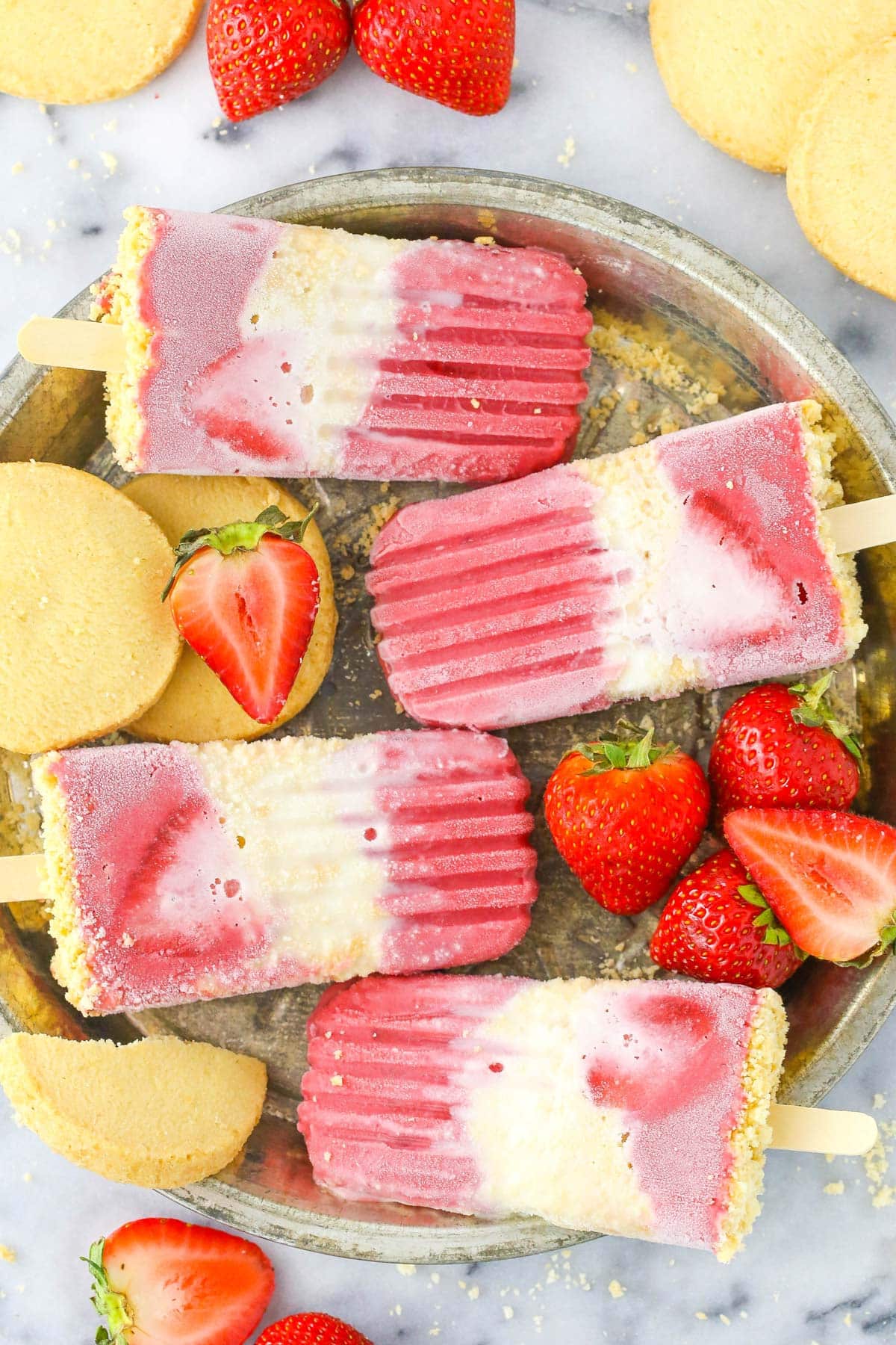 Close up of four strawberry shortcake popsicles on a silver tray.