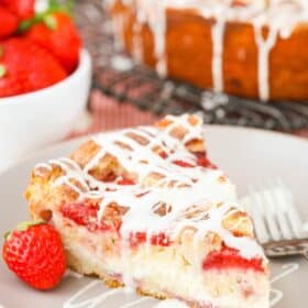 A slice of strawberry snack cake on a white plate drizzled with glaze.