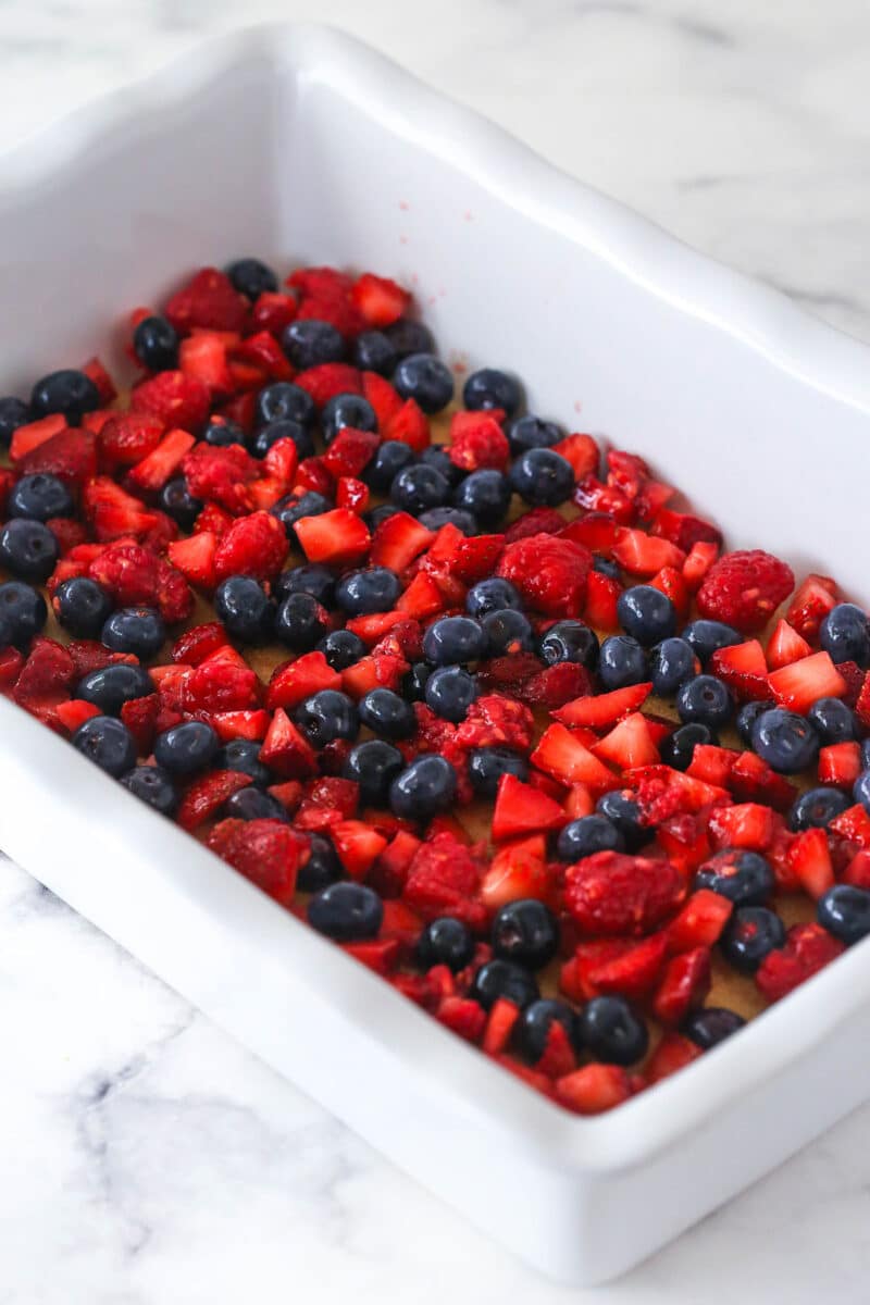layer of berries added on top of ladyfingers in pan