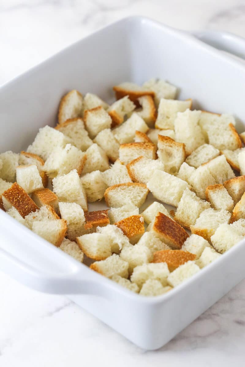 A layer of bread cubes in a baking dish.