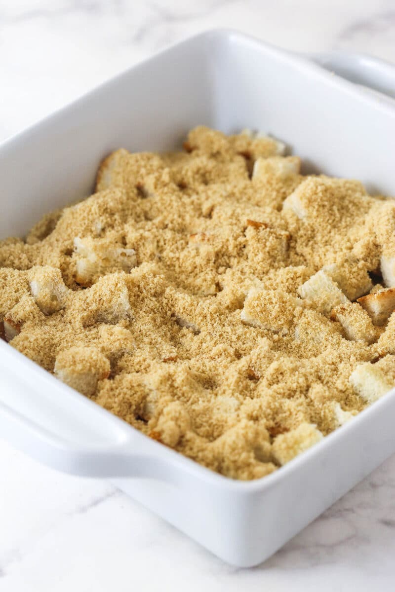Sprinkling brown sugar over bread cubes.